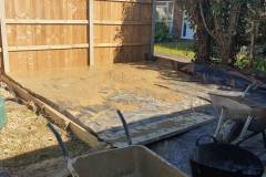 Excavated garden plot with timber shuttering in place and cut back hedges behind